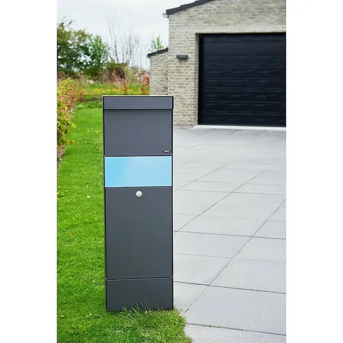 Allux Paketbox Grundform - L x B x H: 28 x 345 x 110 mm, Anthrazit, Stahl, Paketfach - Ein hoher, dunkelgrauer moderner Briefkasten mit hellblauem Panel und Schlüsselschloss, draußen neben einer gepflasterten Auffahrt platziert.