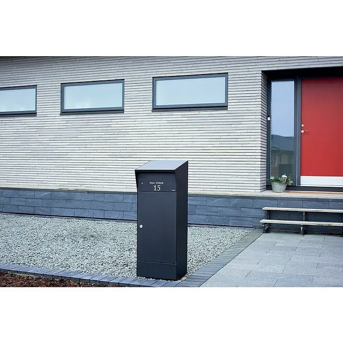 Allux Paketbox Björn mit LED - L x B x H: 365 x 400 x 1.100 mm, Schwarz, Stahl, Paketfach - Ein freistehender dunkelgrauer Metallbriefkasten mit der Aufschrift 'FAM. WEBER 15' vor einem modernen Haus.