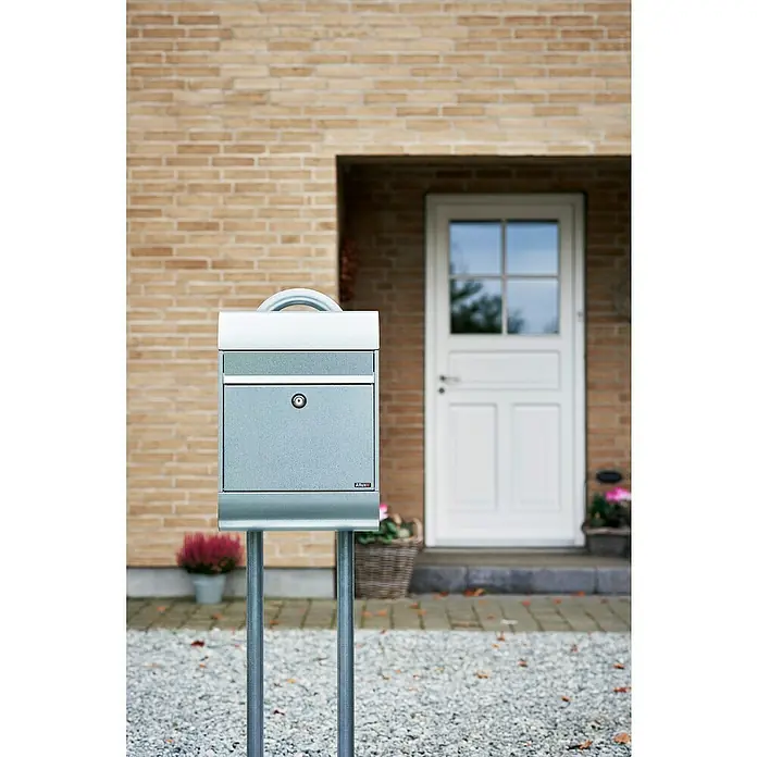 Allux Standbriefkasten 6000 - L x B x H: 170 x 345 x 485 mm, Silber, Stahl - Silbergrauer Metallbriefkasten auf Ständer, vor einem Haus platziert.