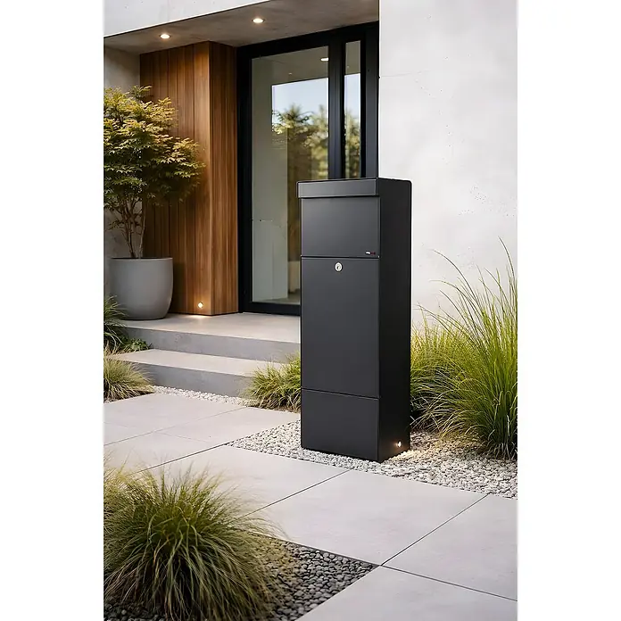 Allux Paketbox Grundform - L x B x H: 28 x 345 x 110 mm, Schwarz, Stahl, Paketfach - Hoher, dunkelgrauer freistehender Briefkasten in modernem Design, im Außenbereich neben einem Gebäudeeingang platziert.