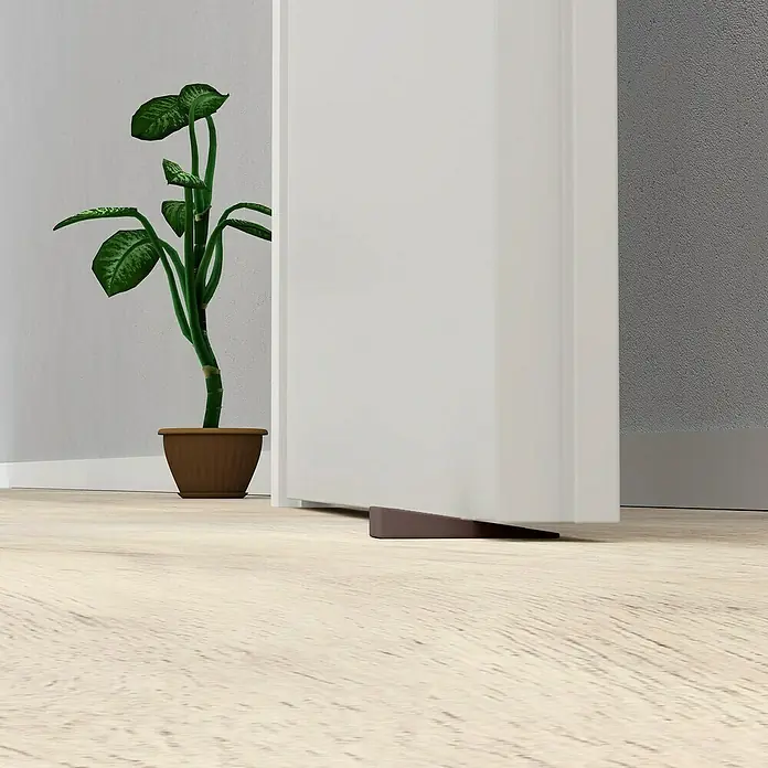 Walteco Türkeil - L x B x H: 50 x 15,5 x 19 mm, Braun, 4 Stk. - Brauner Türstopper hält eine weiße Tür auf hellem Holzboden offen.