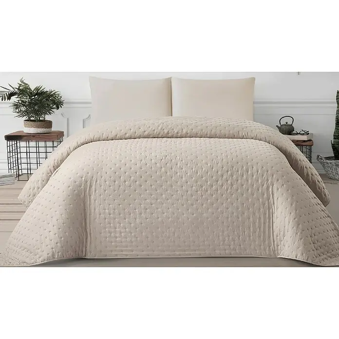 Colcha Darya - 260 x 240 cm, 100% poliéster, Taupe - Colcha acolchada beige claro y dos almohadas a juego sobre una cama.