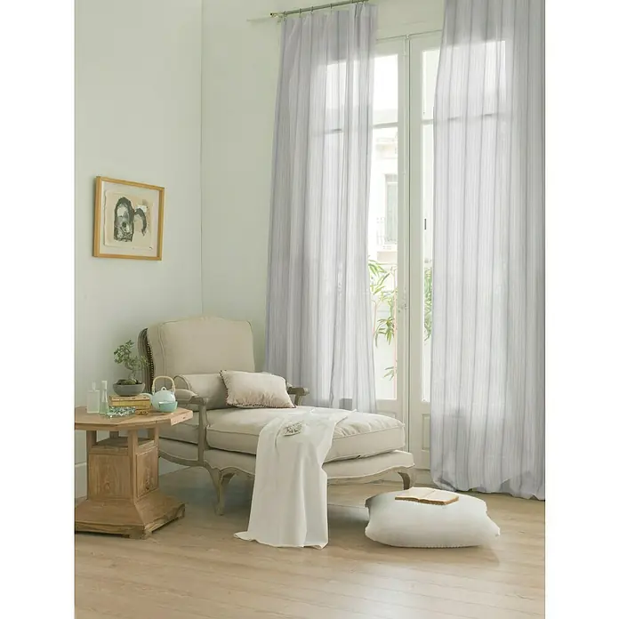 Visillo para ventana Taj - 140 x 250 cm, 100% poliéster, Blanco/gris - Acogedor rincón de lectura con un sillón beige, mesa de madera y cortinas delicadas a rayas para un ambiente tranquilo.