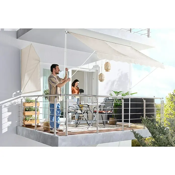 Sunfun Klemmmarkise / Senkrechtmarkise - Beige, Breite: 2,5 m, Ausfall: 1,3 m - Beige Balkonmarkise wird von einem Mann ausgefahren und spendet Schatten. Ein passender Sichtschutz ist ebenfalls zu sehen.