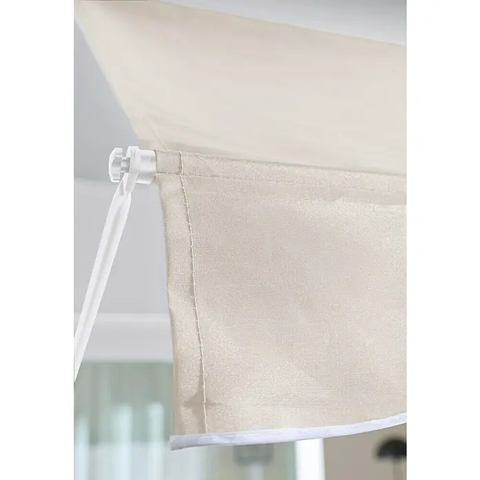 Sunfun Klemmmarkise / Senkrechtmarkise - Beige, Breite: 2,5 m, Ausfall: 1,3 m - Nahaufnahme eines hellbeigen Stoff-Rollos, gehalten von einem weißen Kunststoffhaken, der seine Webstruktur zeigt.