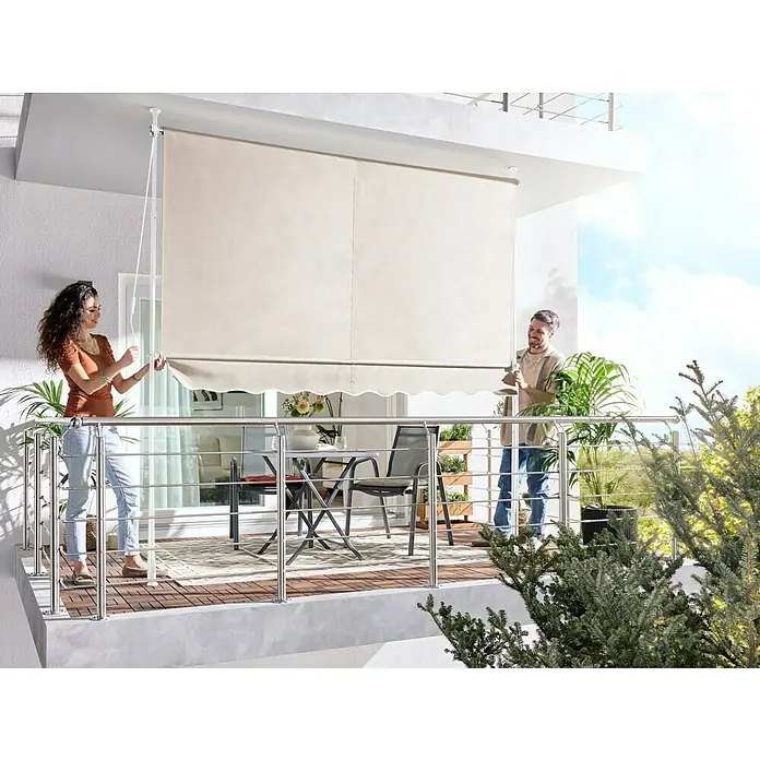 Sunfun Klemmmarkise / Senkrechtmarkise - Beige, Breite: 2,5 m, Ausfall: 1,3 m - Beiger Balkon-Sichtschutz wird von zwei Personen angepasst, spendet Schatten und Privatsphäre auf einem Balkon mit Gartenmöbeln.