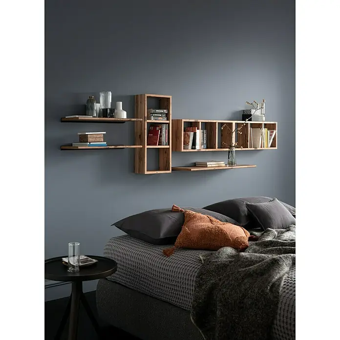 Format Wandregal Triade - L x B x H: 70 x 15 x 30 cm, Alpine - Wandmontierte moduläre Holzregale über einem Bett, gefüllt mit Büchern und Deko, als funktionale und stilvolle Stauraumlösung.