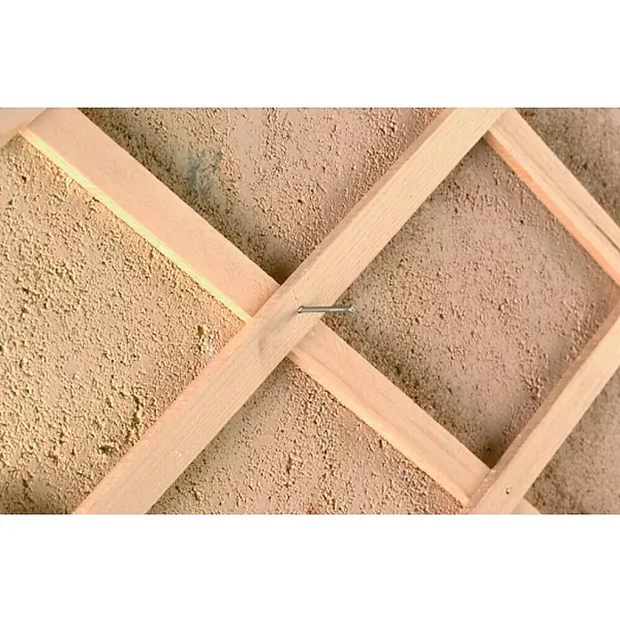 Nortene Celosía Trelliwood - An x Al: 0,5 x 1,5 m, Extensible, Natural - Primer plano de una celosía de madera fijada a una pared con un clavo, mostrando la veta natural de la madera y el detalle de fijación.