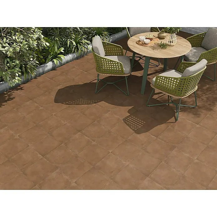Pavimento porcelánico Lucena - 33,3 x 33,3 cm, Marrón, Mate - Baldosas cuadradas marrones cálidas para exterior cubriendo un patio, mostradas con un comedor.