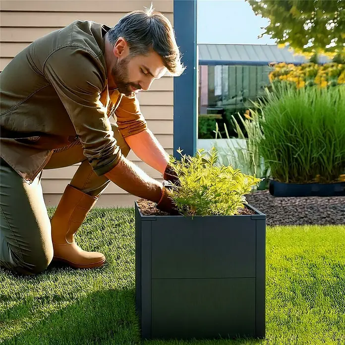 Metzler Hochbeet - 50 x 50 x 50 cm, Stahl, Anthrazit - Anthrazitfarbener quadratischer Pflanzkübel im Garten, ein Mann pflanzt einen grünen Strauch ein. Zeigt praktische Anwendung.