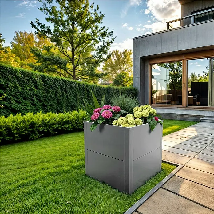 Metzler Hochbeet - 50 x 50 x 50 cm, Stahl, Grau - Graues quadratisches Pflanzgefäß mit rosa und gelben Blumen und Ziergras in einem modernen Garten.