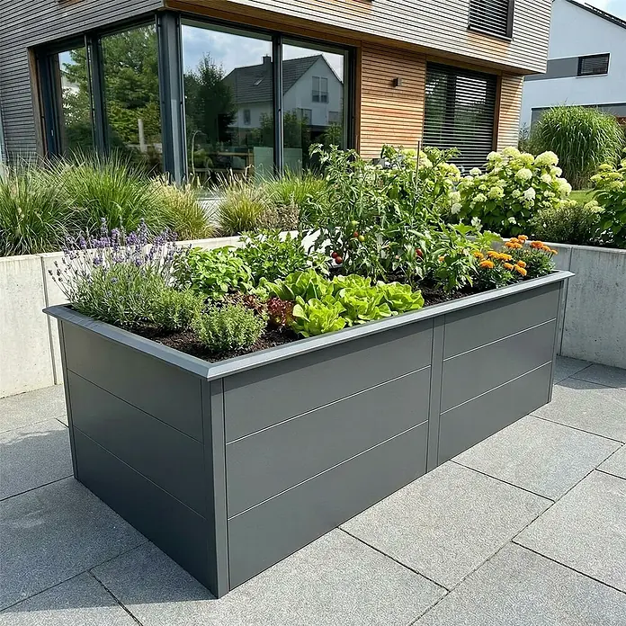 Metzler Hochbeet - 206 x 106 x 77 cm, Stahl, Eisenglimmer - Ein rechteckiges, dunkelgraues Hochbeet aus Metall, gefüllt mit verschiedenen Gemüsesorten und Kräutern, steht auf einer gepflasterten Terrasse.