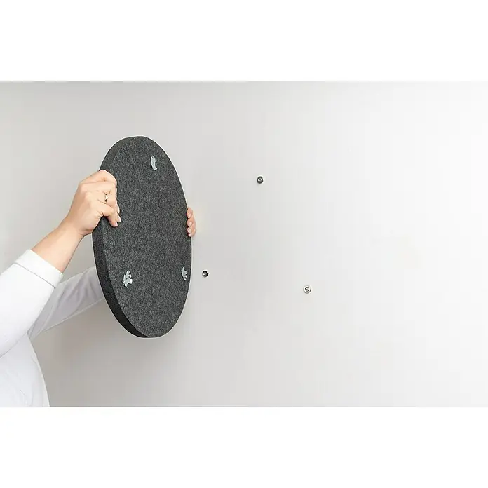 Magnethalter für Akustikpaneele - 3 Stk., Metall - Rundes graues Filz-Akustikpaneel mit Montagehalterungen, von Händen gehalten, wird an einer Wand montiert.