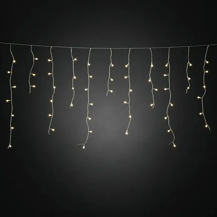 Konstsmide LED-Lichtervorhang Eisregen - Außen, 20,27 m, Warmweiß, 400 Stk., Netzbetrieben - Hängende Lichterkette mit warmweißem Licht vor dunklem Hintergrund. Perfekt für festliche Dekorationen und gemütliche Atmosphären im Innenbereich.