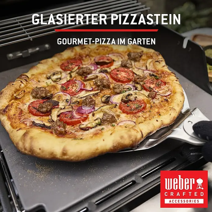 Weber Spirit Gasgrill E-435 - Grillfläche (B x T): 62 x 44 cm, 10,3 kW, Anzahl Brenner: 4 Stk. - Frische Pizza mit Belag auf einem dunkelgrauen, glasierten Pizzastein, vom Grill gehoben.