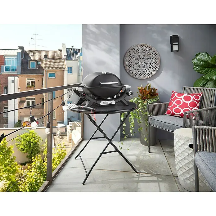 Weber Gasgrill Q 1100 N - Grillfläche (B x T): 45 x 36 cm, 2,94 kW, Anzahl Brenner: 1 Stk. - Schwarzer Weber Q Grill auf einem Klapptisch auf einem Balkon, bereit zum Grillen.
