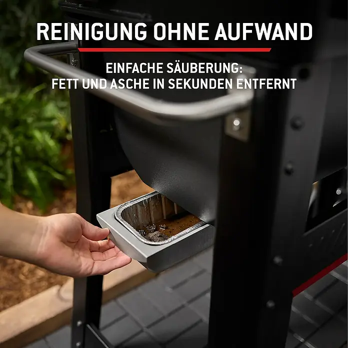 Weber Smoker Smoque - Grillfläche (B x T): 56 x 44,5 cm, Schwarz - Eine Hand entnimmt eine gefüllte Aluschale mit Fett und Asche aus dem Seitenfach eines schwarzen Grills zur einfachen Reinigung.