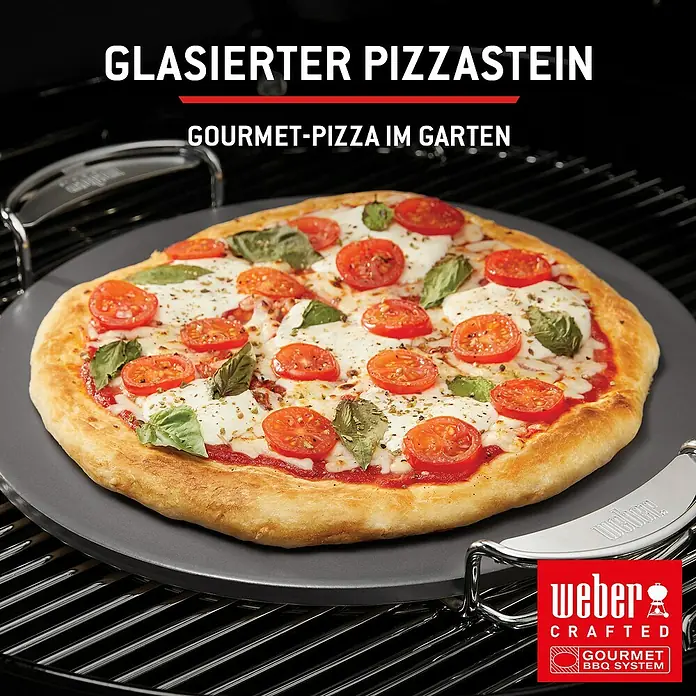 Weber Spirit Gasgrill E-435 - Grillfläche (B x T): 62 x 44 cm, 10,3 kW, Anzahl Brenner: 4 Stk. - Runder, dunkelgrauer glasierter Pizzastein mit Griffen, der eine zubereitete Pizza auf einem Grillrost hält.