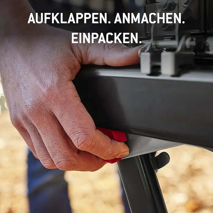 Weber Gasgrill Traveler - Grillfläche (B x T): 63 x 34 cm, 3,8 kW, Anzahl Brenner: 1 Stk. - Hand drückt roten Entriegelungsknopf an einem dunkelgrauen Klappgerät.
