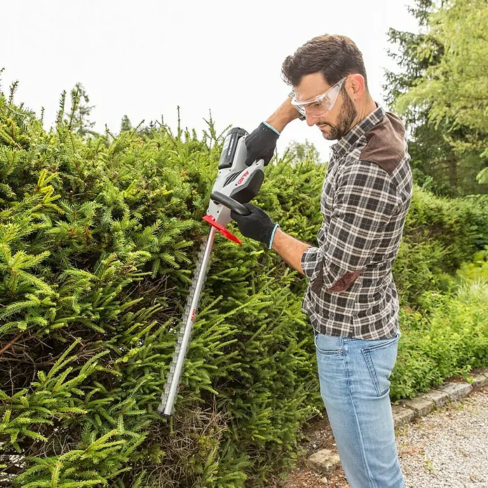 AL-KO 36V Akku-Heckenschere HT 4055 - 36 V, Li-Ionen, Ohne Akku, Schnittlänge: 55 cm - Ein Mann trimmt eine Hecke mit einer AL-KO Akku-Heckenschere, die für präzise Schnitte und einfache Handhabung entwickelt wurde.