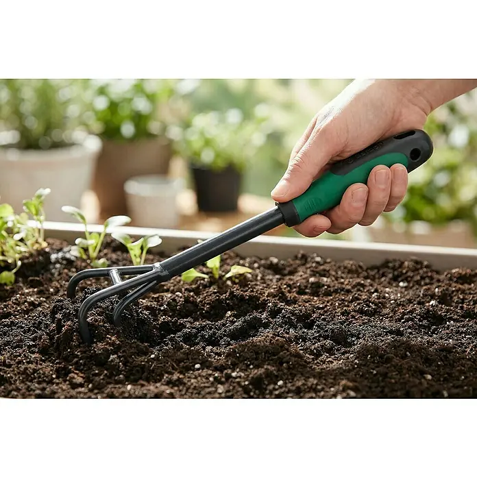 Gardol Hand-Kleingrubber - Arbeitsbreite: 8 cm, Anzahl Zinken: 3, Kurzstiel - Hand hält eine schwarz-grüne Handharke, die Erde in einem Pflanzkasten lockert.