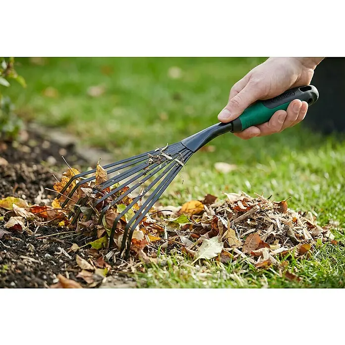 Gardol Hand-Kleinfeger - Arbeitsbreite: 12,5 cm, Anzahl Zinken: 9, Kurzstiel - Eine Hand hält einen kleinen schwarz-grünen Gartenrechen und sammelt Herbstlaub.