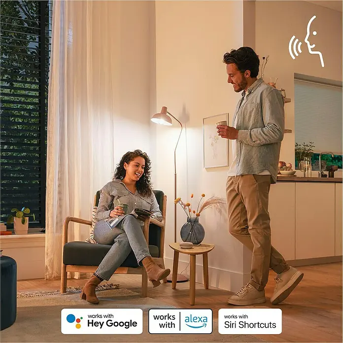 Philips Wiz Smart-LED-Lampe - GU10, Dimmbar, RGBW, 400 lm, 4,7 W, 1 Stk. - Menschen in einem modernen Zuhause nutzen smarte Sprachassistenten wie Google, Alexa und Siri für integrierte Steuerung in einem vernetzten Wohnraum.