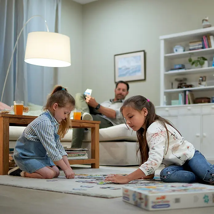 Philips Wiz Smart-LED-Lampe matter - E27, Dimmbar, Neutralweiß, 1.521 lm, 13 W, 1 Stk. - Kinder spielen mit einem bunten Bodenpuzzle auf einem Teppich im Wohnzimmer.