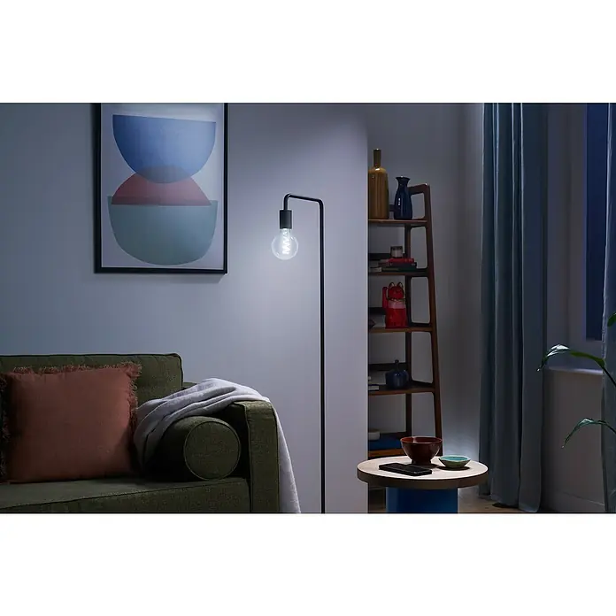 Philips Wiz Smart-LED-Lampe Globe - E27, Dimmbar, RGBW, 470 lm, 6,3 W, 1 Stk. - Eine spiralförmige LED-Smart-Glühbirne beleuchtet ein modernes Wohnzimmer mit hellem, weißem Licht.