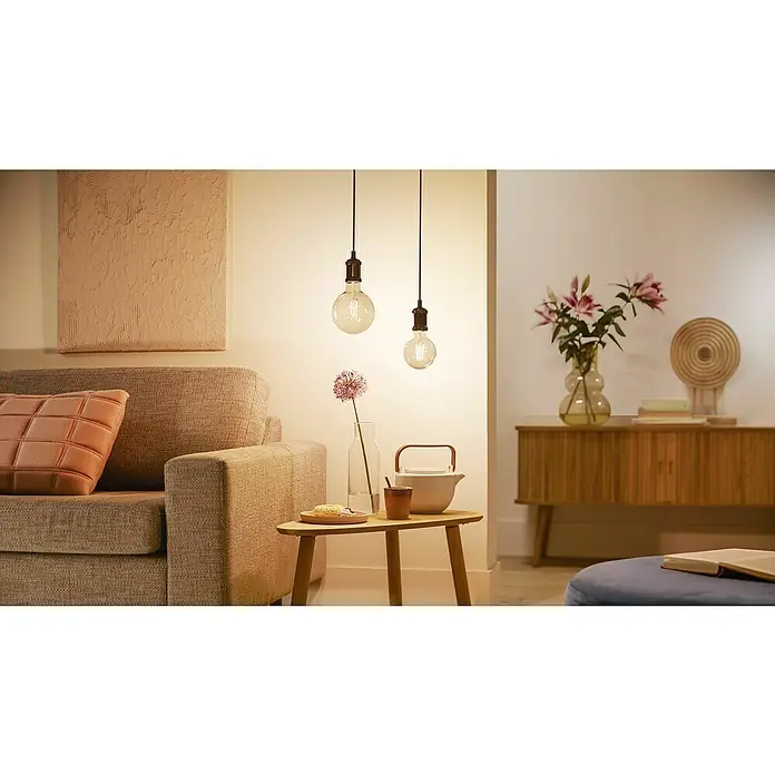Philips Wiz Smart-LED-Lampe - E27, Dimmbar, Neutralweiß, 640 lm, 7 W, 1 Stk. - Zwei klare Pendelleuchten mit schwarzen Fassungen, die warmes Licht in einem gemütlichen Wohnzimmer spenden.