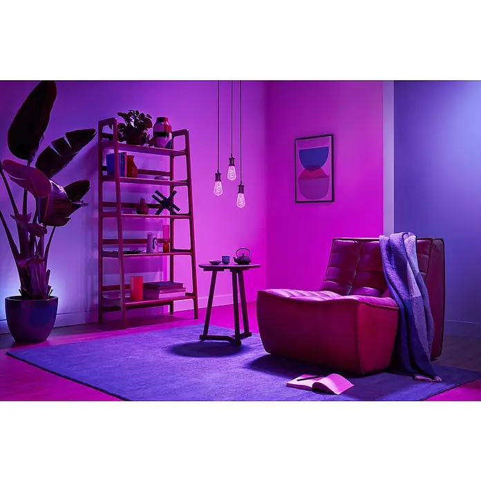 Philips Wiz Smart-LED-Lampe Edison - E27, Dimmbar, RGBW, 470 lm, 6,3 W, 1 Stk. - Ein gemütliches Wohnzimmer, beleuchtet von smarter Beleuchtung in lebhaften Lila- und Rosatönen.