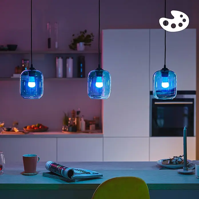 Philips Wiz Smart-LED-Lampe matter - E27, Dimmbar, RGBW, 470 lm, 4,9 W, 1 Stk. - Drei Pendelleuchten aus blauem Glas mit leuchtenden blauen Smart-Glühbirnen beleuchten eine Kücheninsel.