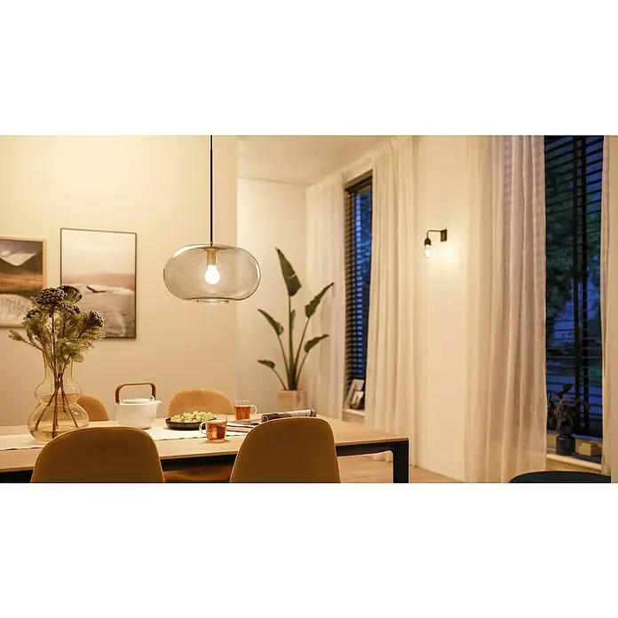 Philips Wiz Smart-LED-Lampe - E27, Dimmbar, Neutralweiß, 806 lm, 7 W, 1 Stk. - Eine Pendelleuchte aus Rauchglas beleuchtet einen Esstisch mit warmem Licht in einem gemütlichen Esszimmer.