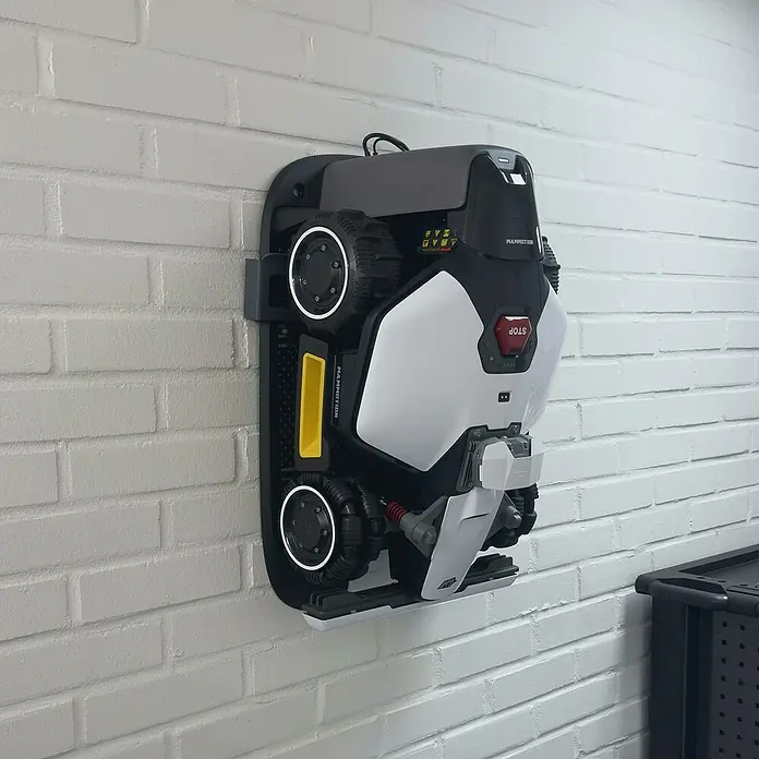 Grimsholm Green Wandhalterung für Rasenmäher - L x B x H: 122 x 15 x 49 cm, Passend für: Mammotion Luba Mini AWD - Schwarz-weißer Mähroboter seitlich montiert, mit großen Rädern und rotem Stopp-Knopf.