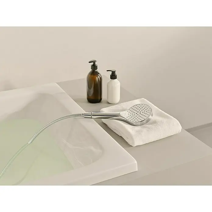 Hansa Viva Handbrause - Durchmesser Handbrause: 11 cm, Chrom - Verchromter Duschkopf mit flexiblem Schlauch auf weißem Handtuch neben Badewanne, mit Seifenspendern.