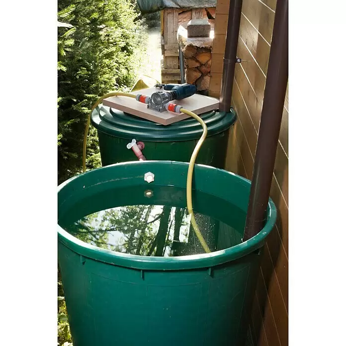 Wolfcraft Bomba - 3.000 l/h, Altura de transporte: 24 m - 30 m, Metal - Bidones de lluvia verdes con una bomba de taladro encima, conectados por mangueras amarillas para transferir agua.
