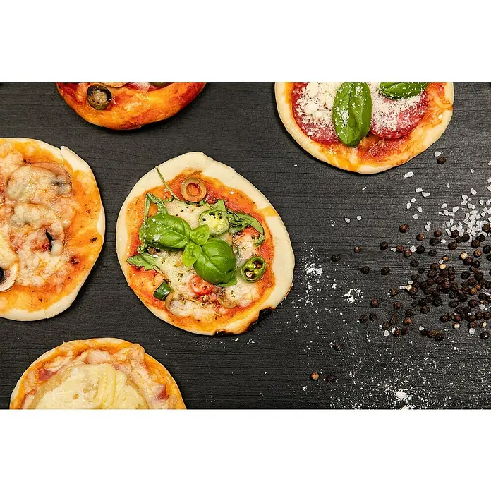 Piardino Bio Basilikum - Ocimum basilicum, Topfgröße: 14 cm - Mehrere kleine Pizzen mit verschiedenen Belägen auf dunklem Untergrund, bestreut mit Salz und Pfeffer.