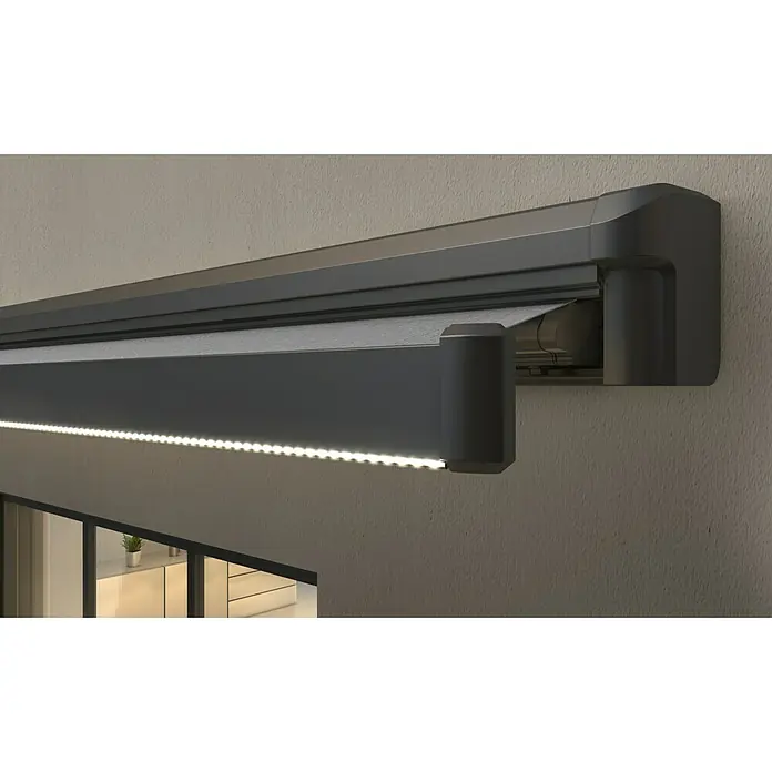 Spettmann LED-Vollkassettenmarkise Sunlite - Grau, Farbe Gestell: Eisenglimmer matt, Breite: 4 m, Ausfall: 2 m - Dunkelgraue Markise mit grauem Stoff und integrierter LED-Beleuchtung, teilweise ausgefahren an einer strukturierten Wand über einem Fenster.
