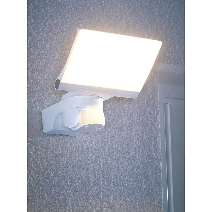 Steinel LED-Sensor-Strahler XLED home 2 S weiß - 13,7 W, L x B x H: 161 x 180 x 218 mm, Weiß, IP44 - Weiße LED-Außenleuchte mit Bewegungsmelder, an rauer Wand montiert und beleuchtet.