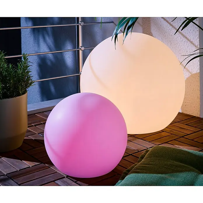 New Garden Solar-Dekoleuchte Buly - Durchmesser: 30 cm, IP65 - Zwei kugelförmige LED-Lampen, eine große cremefarben, eine kleine rosa, auf einem Holzbalkon.