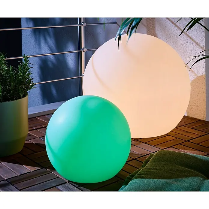 New Garden Solar-Dekoleuchte Buly - Durchmesser: 30 cm, IP65 - Zwei beleuchtete Kugellampen, eine große warmweiße und eine kleine grüne, auf einem Holzbalkonboden.