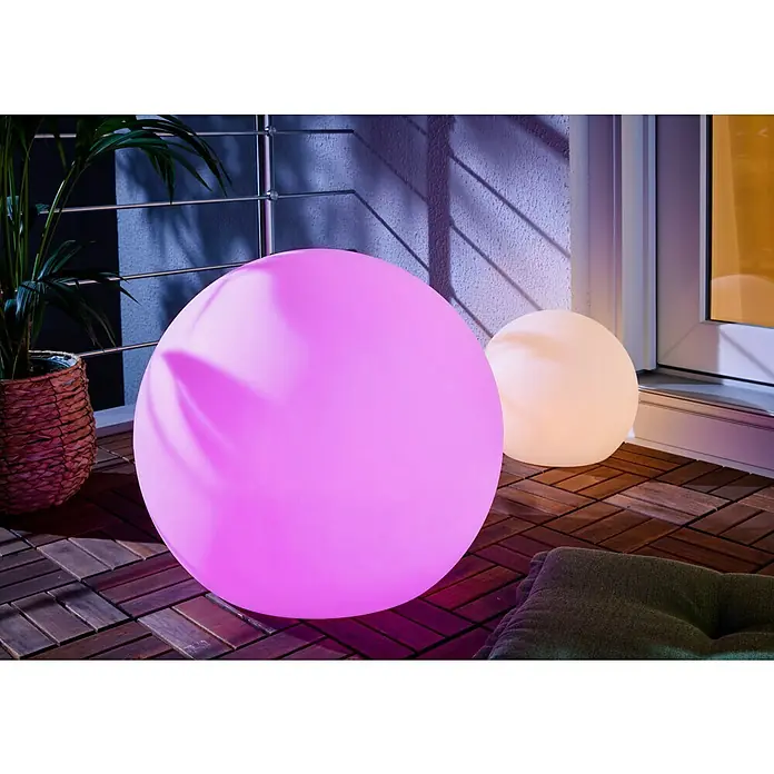 New Garden Solar-Dekoleuchte Buly - Durchmesser: 50 cm, IP65 - Zwei beleuchtete Kugellampen, eine große lila, eine kleinere weiße, auf einem Holzterrassenboden.