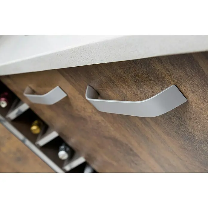 Rei Möbelgriff - Lochabstand: 160 mm, Aluminium, Aluminium, Gebogen - Moderne silber-graue geschwungene Griffe an einem Holzschrank, mit einer weißen Arbeitsplatte und Weinlagerung darunter.