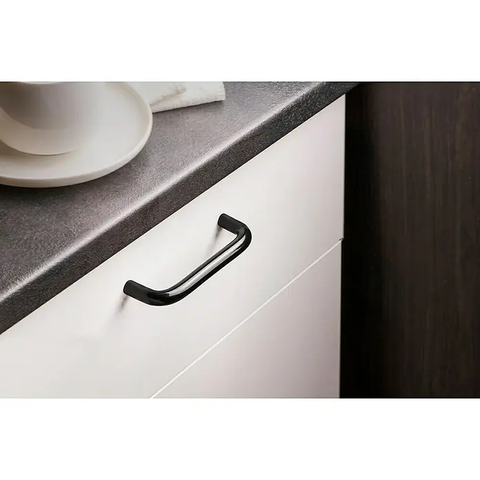 Rei Möbelgriff - Lochabstand: 96 mm, Kunststoff, Schwarz - Schwarzer Schrankgriff an einer weißen Schublade, kontrastiert mit einer dunklen Arbeitsplatte und einem Holzschrank.
