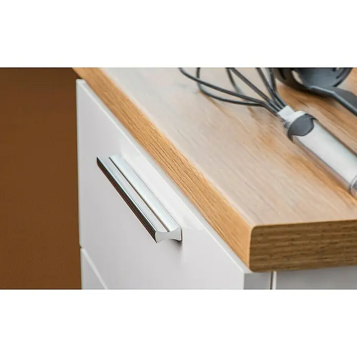 Rei Möbelgriff - Lochabstand: 160 mm, Aluminium, Chrom, L x B x H: 120 x 9 x 17 mm - Nahaufnahme einer hellen Küchenarbeitsplatte aus Holz mit weißem Schrank, silbernem Griff, Schneebesen und Utensil.