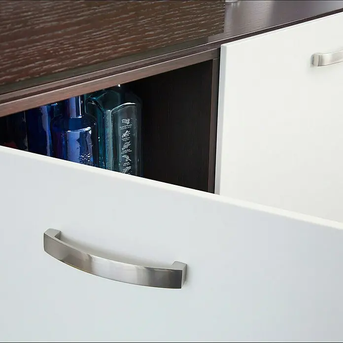 Rei Möbelgriff - Lochabstand: 128 mm, Aluminium, Nickel, Trend - Offene weiße Schublade mit gebürstetem Metallgriff, die blaue Flaschen in einem dunkelbraunen Schrank zeigt.