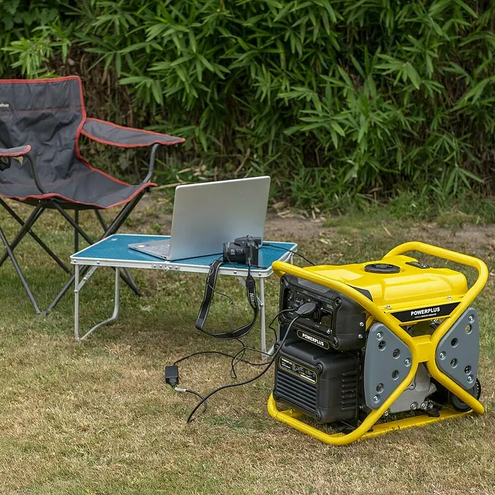 PowerPlus Generador POWX5230 - 3 kW, Volumen del depósito: 10 l - Generador Powerplus amarillo y negro alimentando un portátil y una cámara al aire libre, junto a una silla de camping.