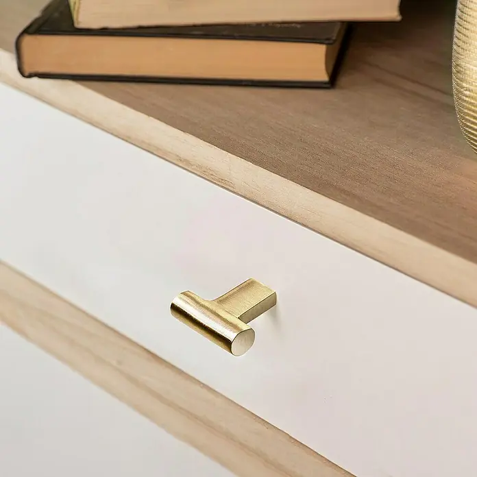 Rei Tirador para muebles - L x Al: 33 x 31 mm, Latón vintage - Un cajón blanco con tirador de barra en T de latón, parte de un mueble de madera con libros apilados encima.