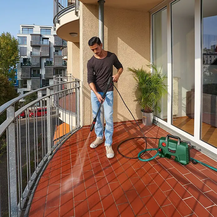 Bosch Hochdruckreiniger EasyAquatak 120 - 1.500 W - Der Bosch Hochdruckreiniger im Einsatz auf einem Balkon, wo ein Mann die Fliesen reinigt. Das Gerät ist kompakt und benutzerfreundlich.