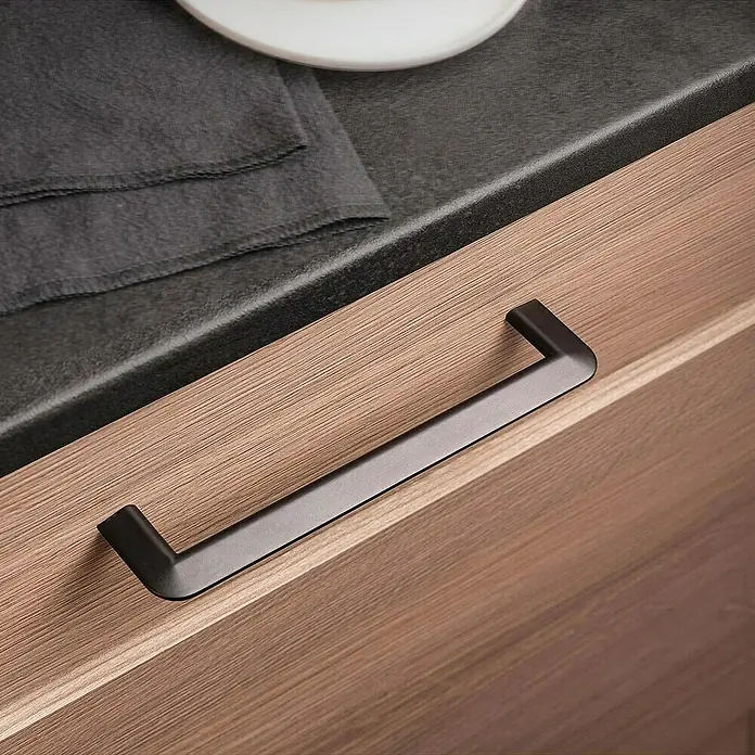 Rei Möbelgriff - Lochabstand: 160 mm, Sonstige, Schwarz, L x B x H: 181 x 8 x 35 mm - Schwarzer matter Griff an einem Holzschrank oder einer Schublade, mit einer dunklen Arbeitsplatte darüber.